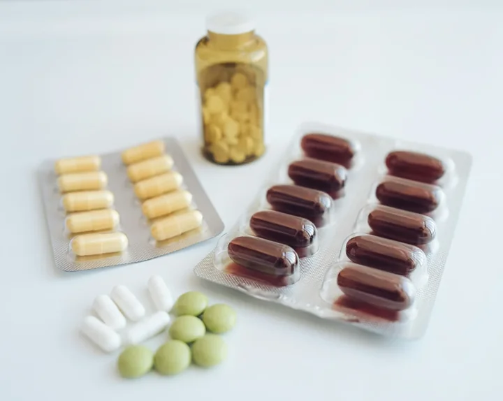 Blister packs of capsules and tablets beside a bottle on a white surface